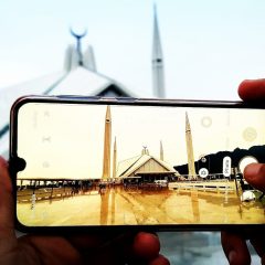 person holding silver iphone 6 taking photo of white and brown tower