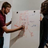 man drawing on dry-erase board