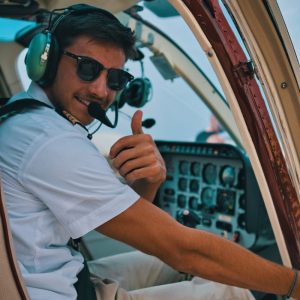 Photo by Roman Rezor a man sitting in the cockpit of a plane giving a thumbs up
